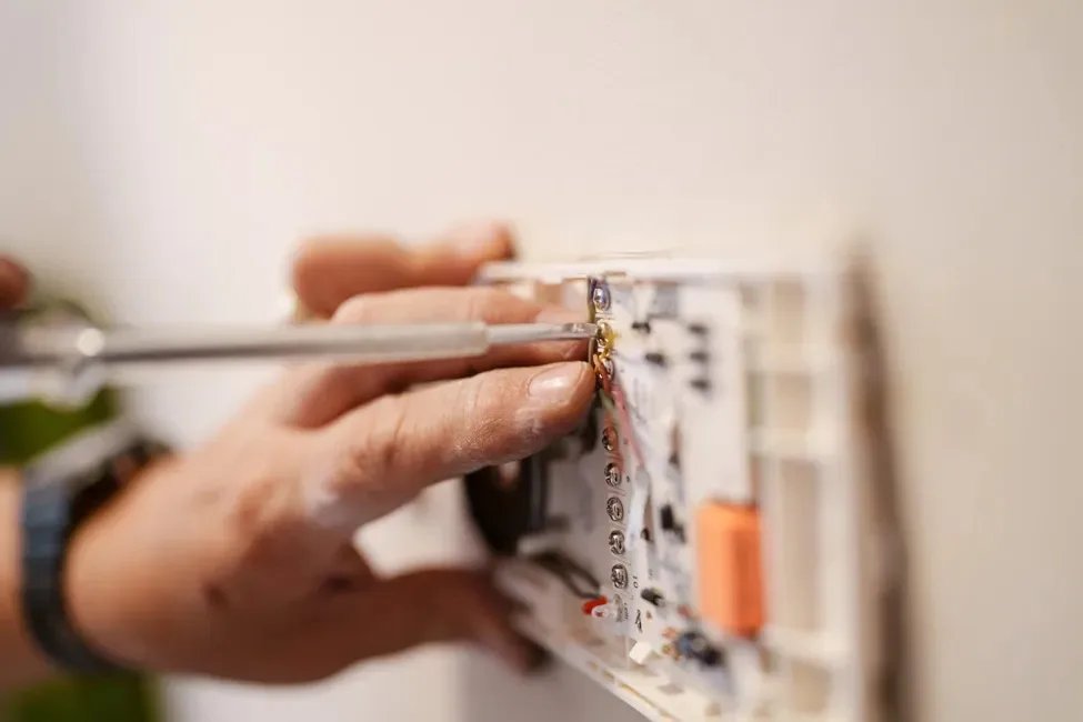 Wall plate wiring being repaired with a screwdriver